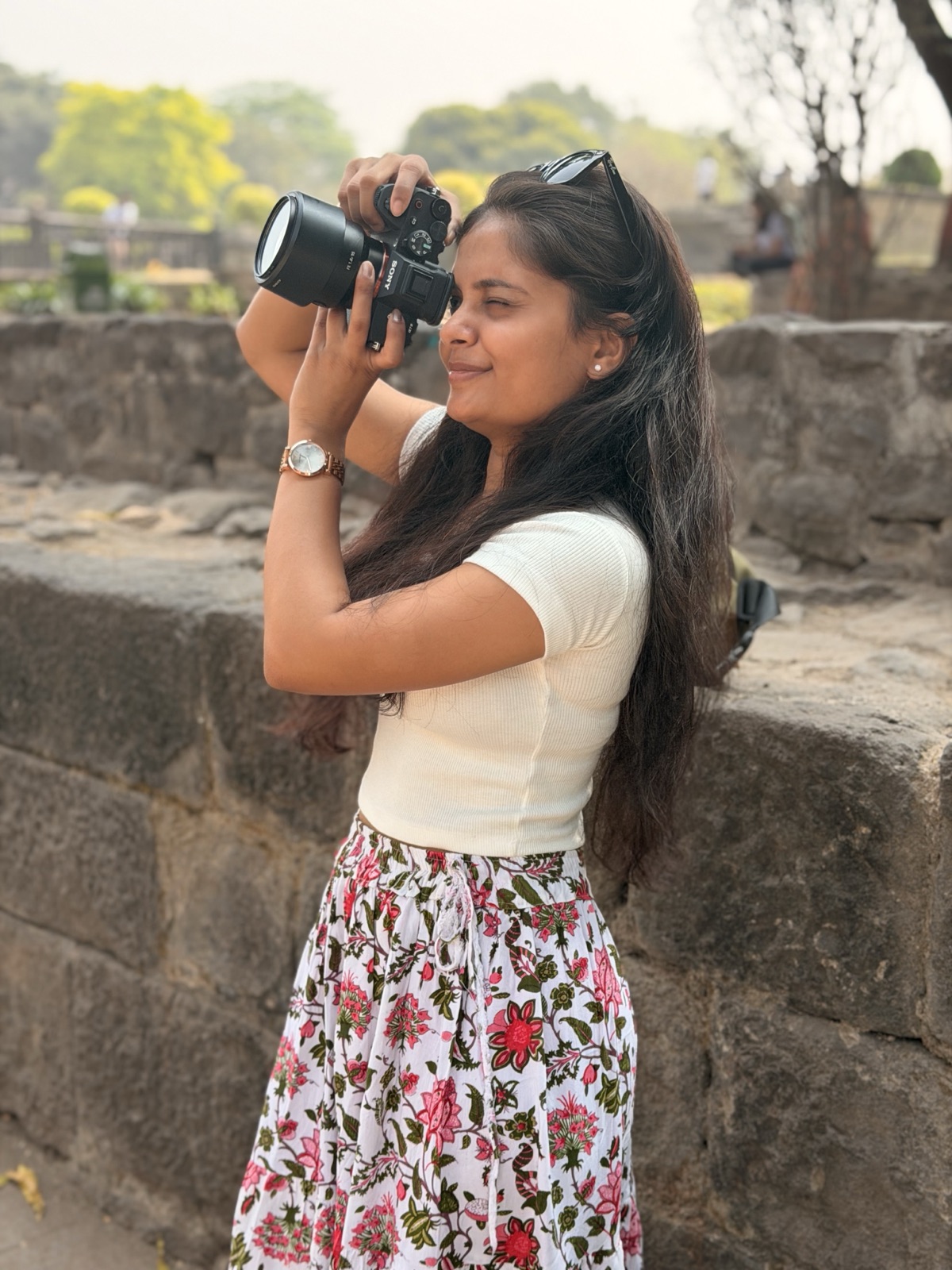 A woman photographing from a stone rampart with a Sony mirrorless camera