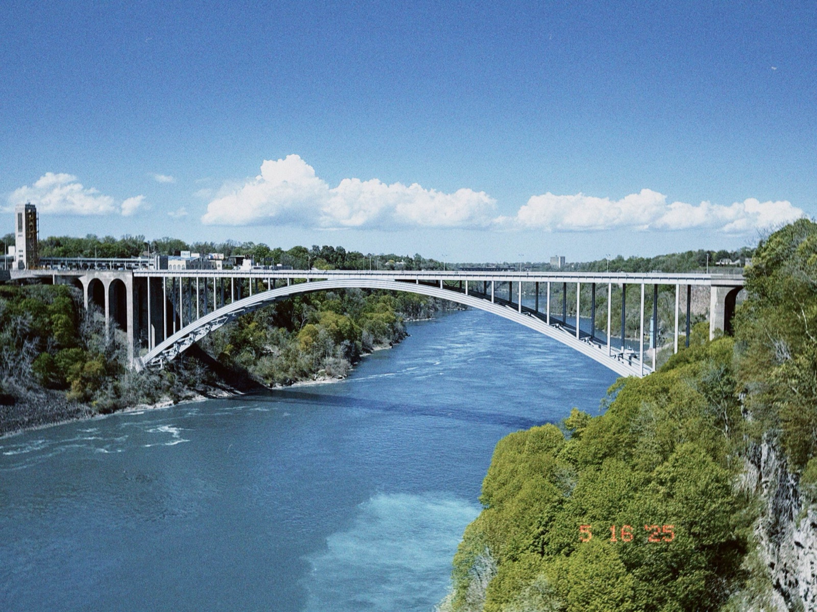 Rainbow Bridge arching over the blue-green Niagara River, film date stamp in corner